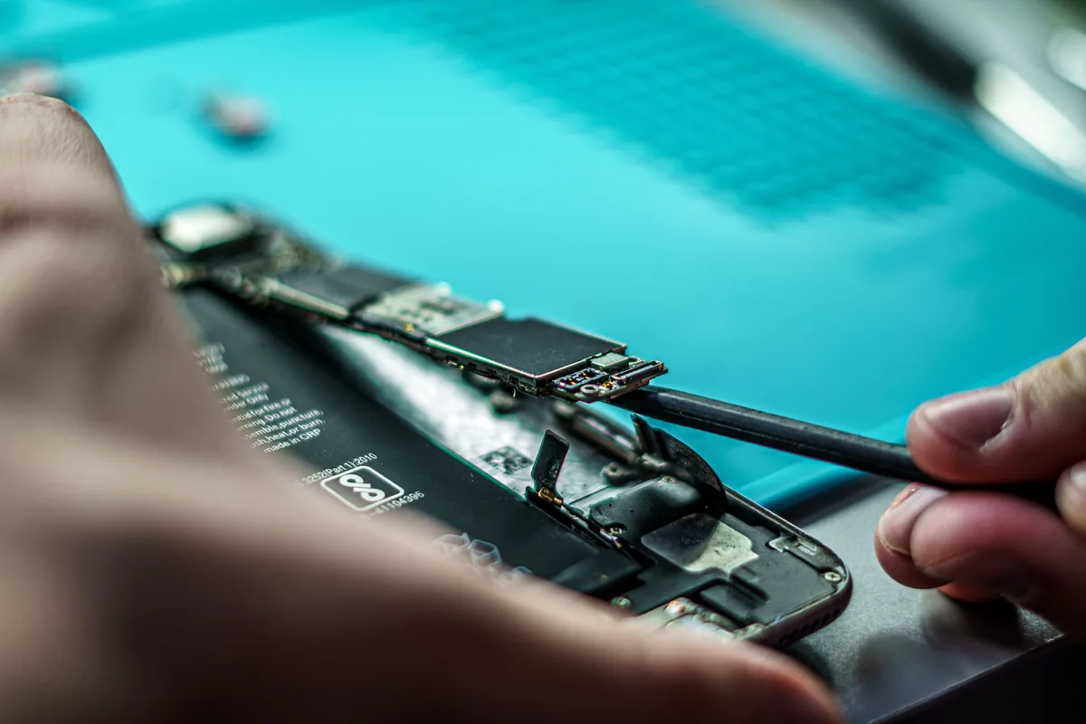 Técnico reparando la placa base de un móvil durante el proceso de reacondicionado